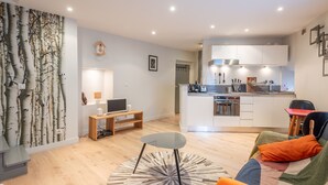 A modern apartment with a living room, dining area, and kitchen.
