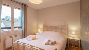 Een slaapkamer met een bed, twee bedlampen, een raam en een radiator.