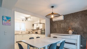 Een moderne keuken met witte kasten, een eettafel met vier stoelen en een wand met een bijzondere textuur.