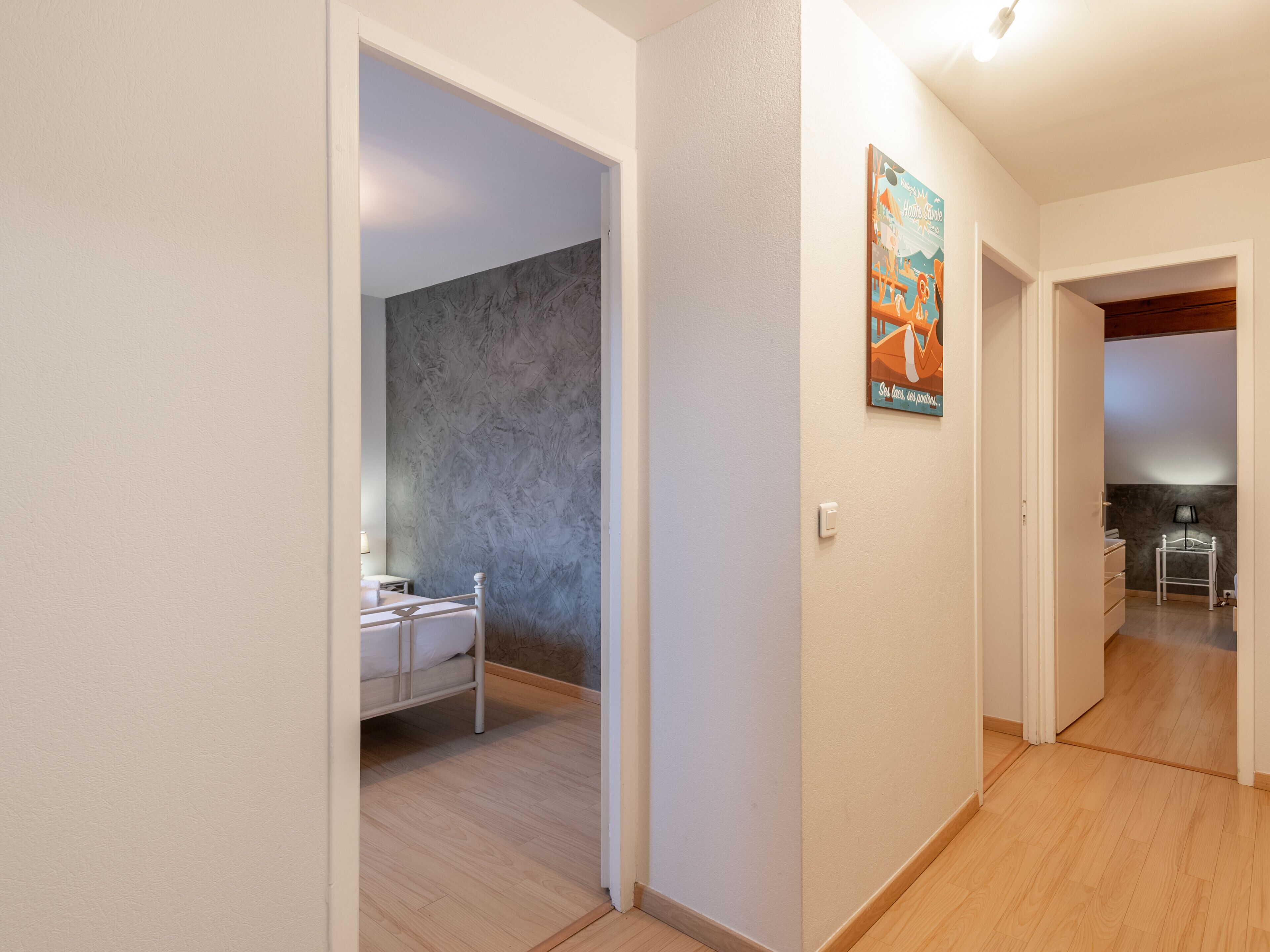 Un couloir avec des toilettes sur la gauche, un porte-manteau et une affiche accrochée au mur.
