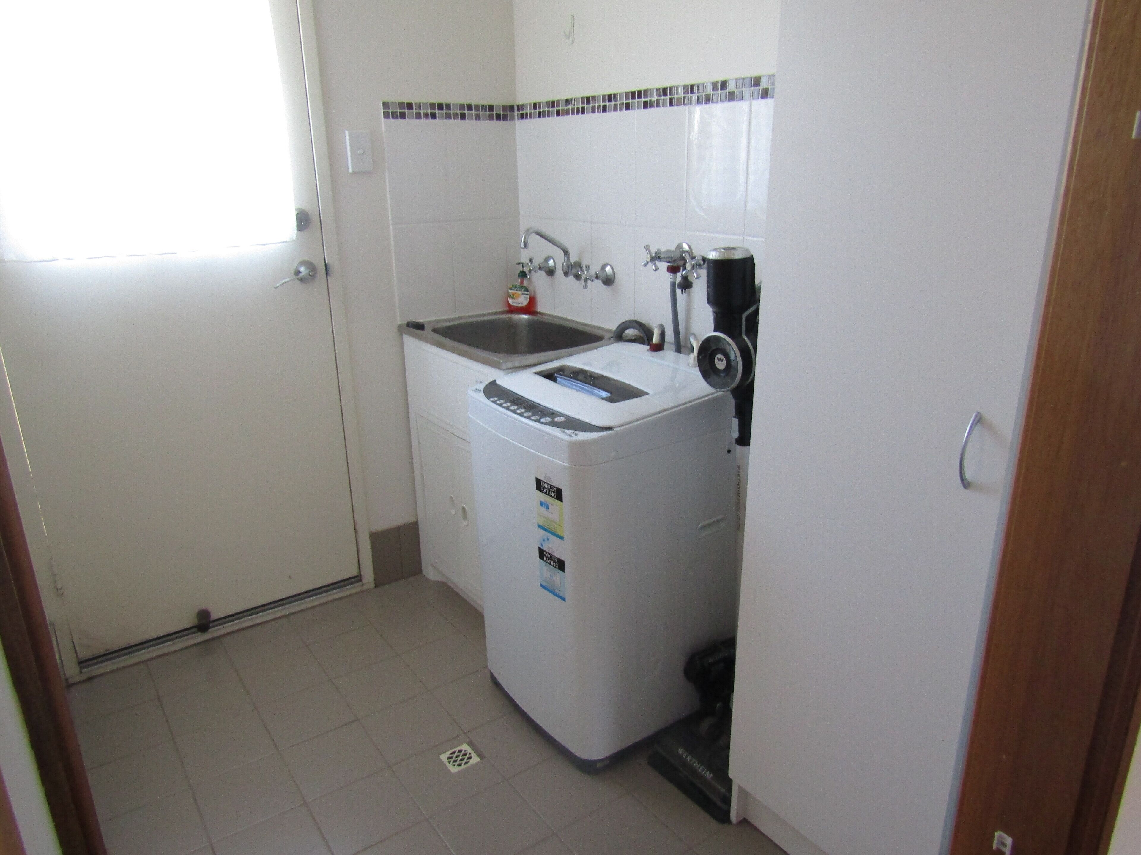 Une cuisine compacte équipée d’un lave-linge intégré, d’un évier et d’une machine à café.