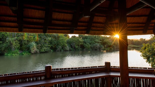 Una terraza de madera con vistas a un río y árboles.