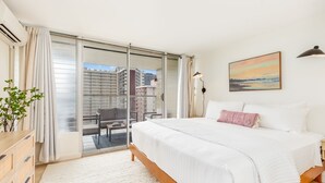 Una habitación de hotel moderna con una cama grande, vistas a la ciudad a través de ventanales del suelo al techo, un cuadro en la pared y un balcón pequeño con una silla.