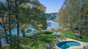 Un jardin avec une piscine, un foyer extérieur et une vue sur un lac.