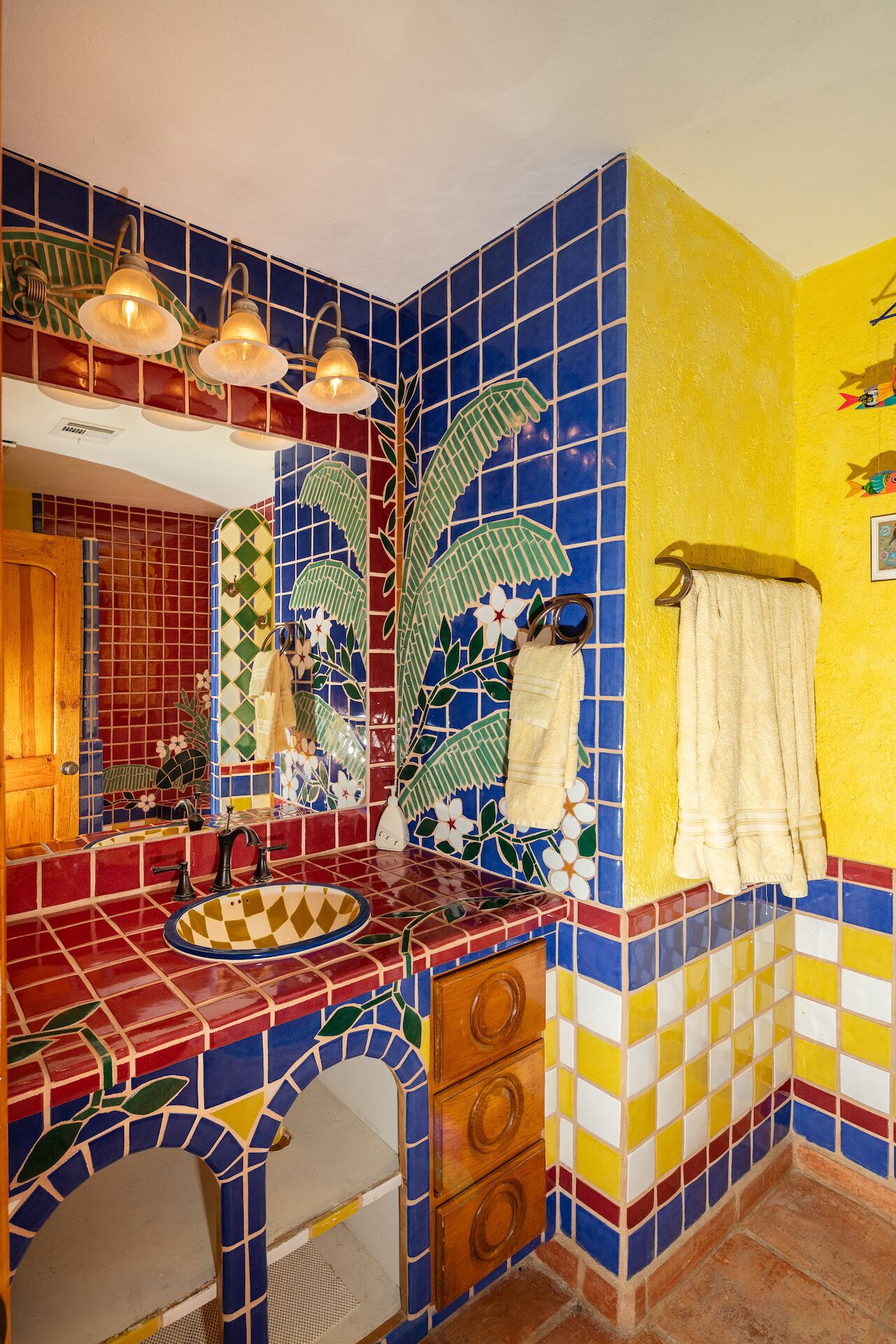 A bathroom with a colorful mosaic tile design, a sink with a decorative basin, and a towel rack with a towel.