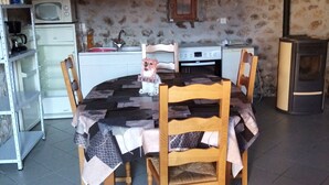 Un comedor rústico con una mesa redonda, sillas de madera, un refrigerador blanco, un microondas y una estufa.