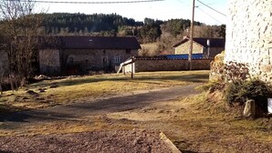 Una propiedad rural con edificios de piedra, camino de grava y zona ajardinada.