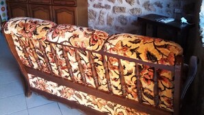 Una habitación con sofá, armarios de madera, pared de piedra y televisor.