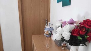 A wooden table with a vase of flowers, a decorative vase, and a small candle. - Chez Moustapha (San Juan de Aznalfarache)