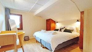 Un dormitorio con cama, mesita de noche, silla y ventana.