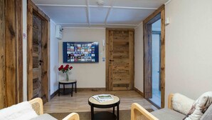 Una habitación acogedora con una puerta de madera, una mesa redonda con una revista y un sofá.