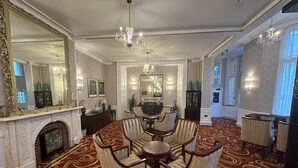 A spacious room with a large mirror, a chandelier, a fireplace, and a dining area with chairs and a table. - Botleigh Grange Hotel & Spa (Southampton)