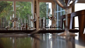 A dining table with several wine glasses and a pitcher, set against a window with a view of greenery. - Botleigh Grange Hotel & Spa (Southampton)