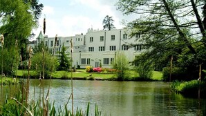 A large, white building with multiple windows and a well-maintained garden with a pond in the foreground. - Botleigh Grange Hotel & Spa (Southampton)