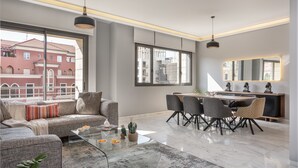 Uma sala de estar moderna com um sofá, mesa de centro e área de jantar com cadeiras e uma mesa.