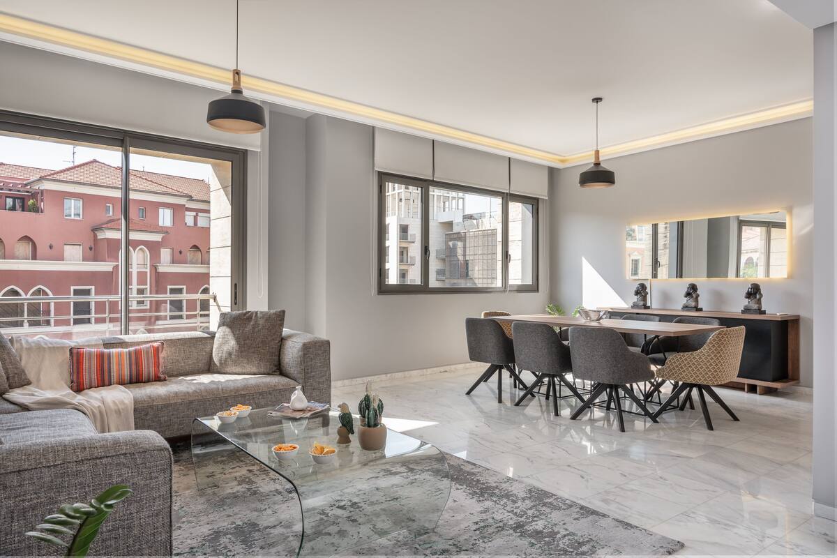 A modern living room with a sofa, coffee table, and dining area with chairs and a table.