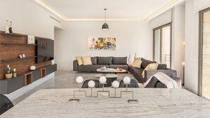Uma sala de estar moderna com um sofá cinzento, uma mesa de centro e uma TV numa estante de madeira.