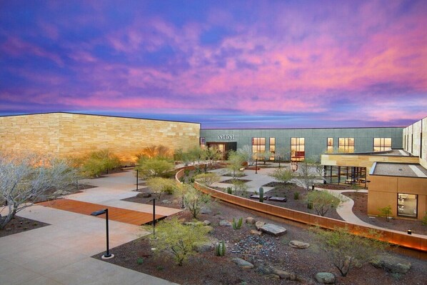 A modern building with a stone facade and a courtyard with landscaping.