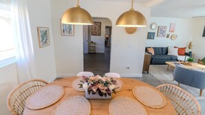 A modern living room with a dining area, featuring a wooden table, wicker chairs, and a sofa. - 2BR Central Phoenix - Backyard - Near Sky Harbor (Phoenix)