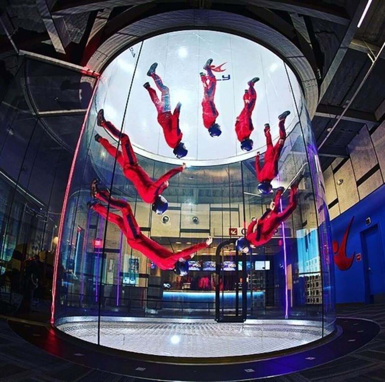 A circular glass enclosure with multiple people performing acrobatics.