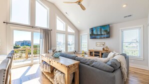 En rummelig stue med en stor grå sofa, et træ sofabord og en loftventilator.