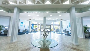 Eine großzügige Lobby mit einem Glas-Tisch in der Mitte, großen Fenstern und einem modernen Deckenstil.