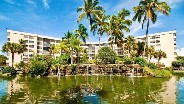 Ein Hotel mit Pool, Palmen und einem Wasserfall.