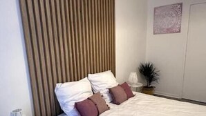 Une chambre à coucher moderne avec un grand lit, une table de chevet, une lampe et un luminaire fixé au mur.
