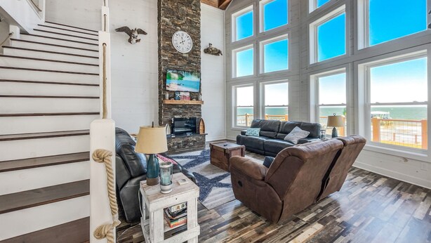 Uma sala de estar ampla com lareira, assentos confortáveis e grandes janelas com vista panorâmica.