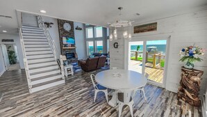 Uma sala de estar ampla com escada, mesa de jantar e vista para o oceano.