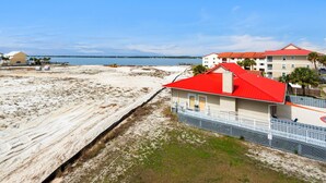 Un hôtel situé en bord de mer, avec un toit rouge, une plage de sable et une vue dégagée sur l’océan.