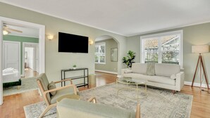 Ein modernes Wohnzimmer mit einer Couch, Sesseln, einem Couchtisch und einem Fernseher.