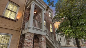 Un bâtiment à deux étages, doté d’une façade en briques, d’un balcon avec une balustrade et d’un escalier menant au deuxième étage.
