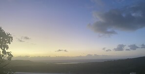 Paisagem costeira com vista para o mar e colinas ao longe.