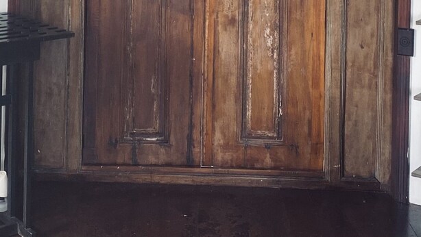 A large wooden door with intricate carvings and two small lights on either side.