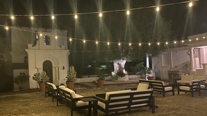 An outdoor patio area with string lights, seating arrangements, and potted plants.