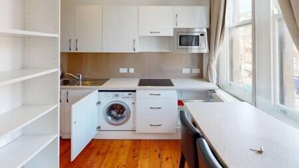 A compact kitchen with a washing machine, a microwave, and a window with curtains. - Heart of Nottingham - turret studio (Nottingham)