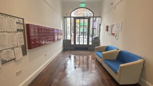A hallway with a blue sofa, wooden flooring, a bulletin board, and a door leading outside. - Heart of Nottingham - turret studio (Nottingham)