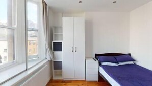 A bedroom with a bed, a wardrobe, and a radiator. - Heart of Nottingham - turret studio (Nottingham)