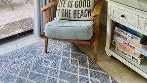 Un rincón acogedor para leer, con una silla, una estantería y una ventana con cortinas.
