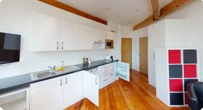 A modern kitchen with white cabinets, a black countertop, and a wooden floor. - Heart of Nottingham-Great City Views (Nottingham)