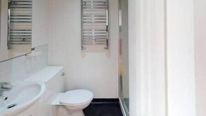 Une salle de bain avec un lavabo blanc, des toilettes et un porte-serviettes.