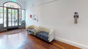 A reception area with a wooden floor, a white sofa, and a glass door leading outside. - Quieter Studio for City Centre Location (Nottingham)