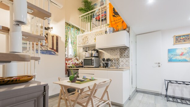 Une cuisine compacte avec un coin repas, des meubles blancs et une petite table avec des chaises.