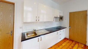 A kitchen with white cabinets, a stainless steel sink, and a microwave. - Studio with Great City Views (Nottingham)