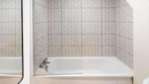 A bathroom with a bathtub and tiled walls. - Lovely 2 bedroom flat with free parking (Nottingham)