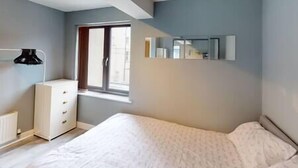 A bedroom with a bed, a dresser, a window, and a mirror on the wall. - Lovely 2 bedroom flat with free parking (Nottingham)