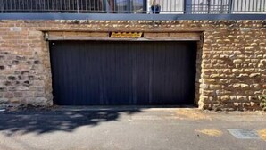 A closed garage door with a stone wall and a metal fence above it. - Lovely 2 bedroom flat with free parking (Nottingham)