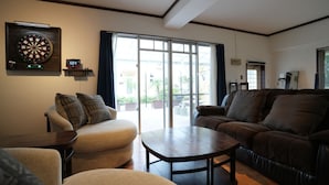 A living room with a dartboard, a digital clock, and a large window. - CINEMA RESORTS 4 (Motobu)