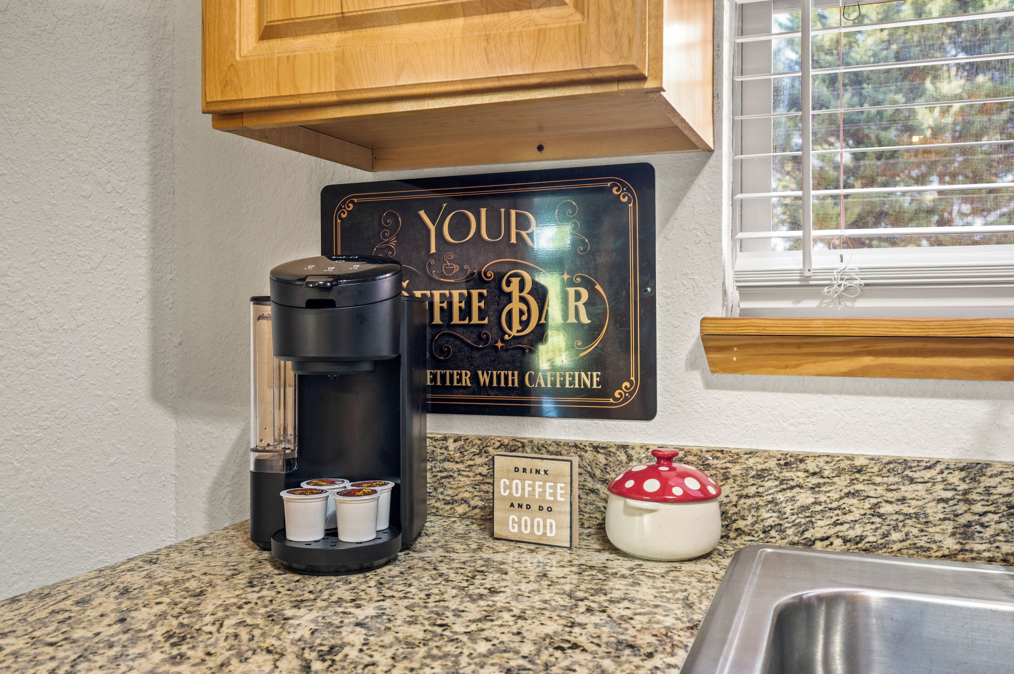 A coffee maker, a sign reading "YOUR COFFEE BAR," and a small sign saying "DRINK COFFEE AND DO GOOD."